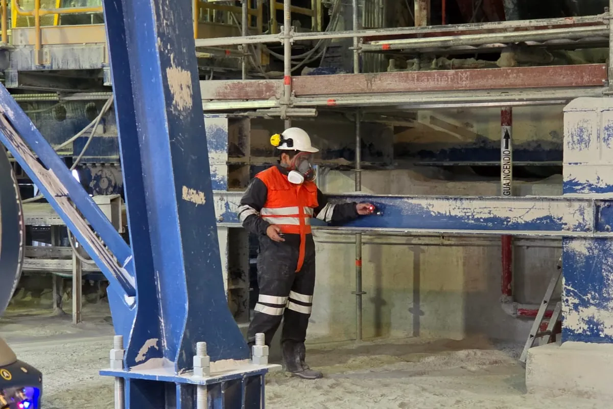 Técnico apoyando el reflector del laser tracker sobre una estructura de planta durante una medición dimensional
